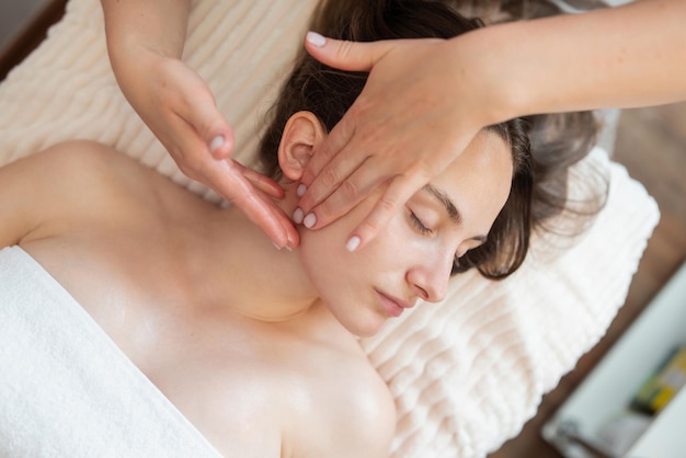 Gros plan des mains d'un médecin cosmétologue donnant un massage facial au spa à une cliente