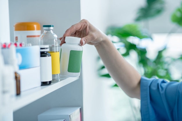 Gros plan des mains de médecins prenant une bouteille avec des pilules