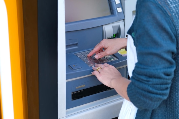 Gros plan des mains d'une personne à l'aide du clavier ATM