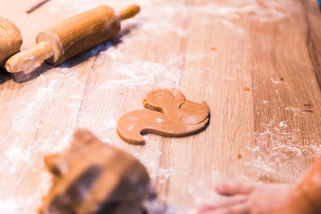 Gros plan des mains pétrissant une pâte sur une table en bois