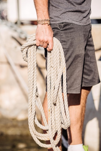 Gros plan des mains de plaisancier avec des cordes de yacht