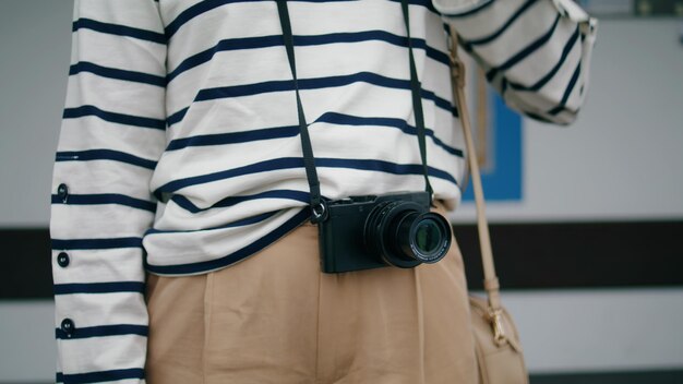 Photo gros plan mains prenant une caméra analogique focalisée sur une fille prenant des photos à l'extérieur