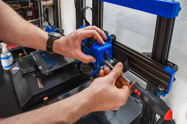 Gros plan des mains d'un technicien effectuant la maintenance d'une imprimante 3D