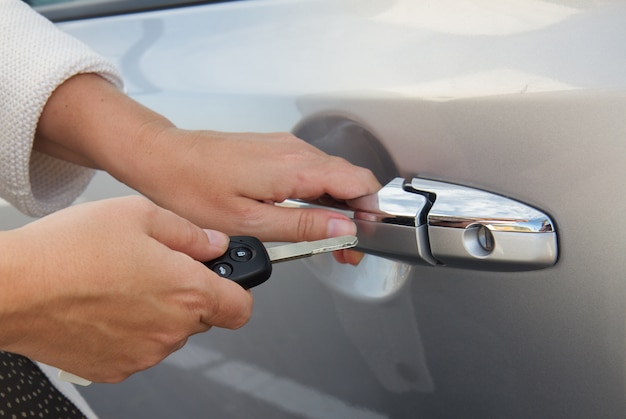Gros plan des mains avec télécommande clé de voiture ouvrant la porte de voiture en métal gris