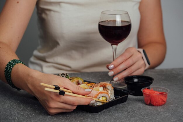 Gros plan des mains tenant un rouleau de sushi avec des baguettes