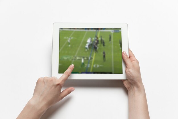 Gros plan sur les mains tenant la tablette en regardant le sport, le football en ligne en streaming du championnat. Nouvelles règles pendant l'épidémie de coronavirus et le verrouillage des pays. Concept de sport, compétition, technologies.