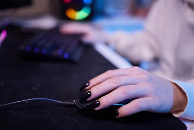 Gros plan mains tourné asie fille gamer utiliser le clavier et le contrôleur de souris jouer à un jeu vidéo avec un ordinateur néon dans le bureau à la maison jeu de streaming esport en ligne en ligne concept d'activité de quarantaine à domicile