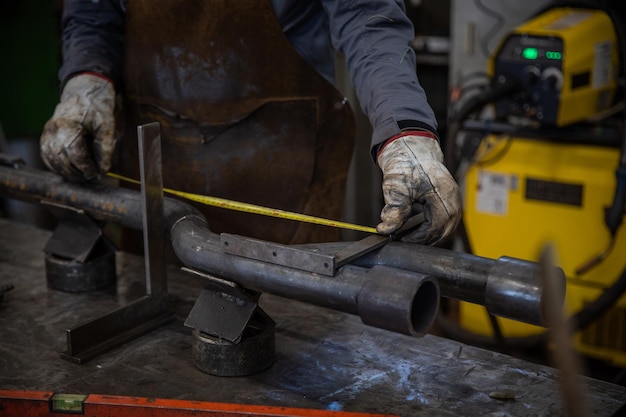 Gros plan sur les mains d'un travailleur mesurant un tuyau dans une usine