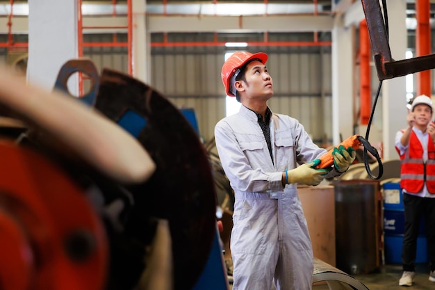 Gros plan des mains des travailleurs contrôlent le pont roulant intérieur pour soulever l'objet de construction métallique sur l'usine de tôle