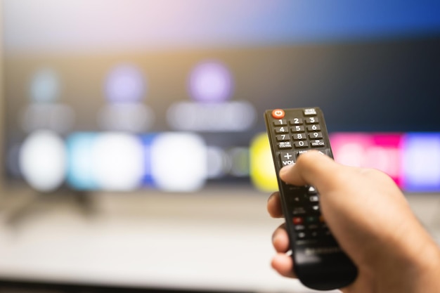 Gros plan mâle main tenant la télécommande pointant pour changer le programme de télévision.