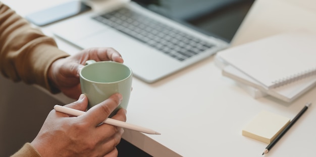 Gros plan, mâle, pigiste, tenue, a, tasse café, alors, travailler, dans, confortable, pièce