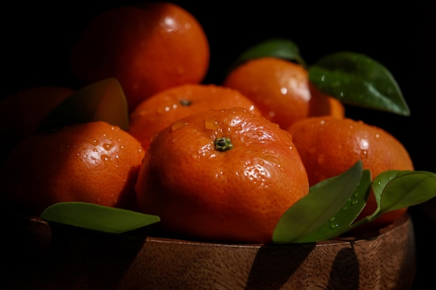 gros plan de mandarines avec des feuilles et des gouttes d'eau, fond noir