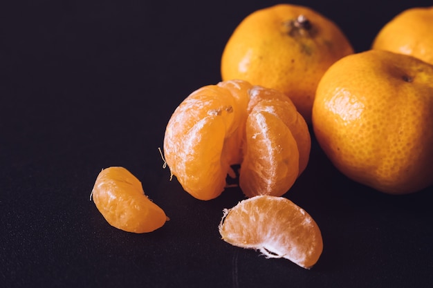 Gros plan de mandarines fraîches, fruits orange sur fond sombre.