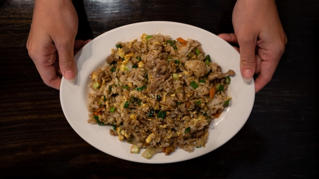 Gros plan de manger un riz frit taïwanais populaire avec des œufs de porc et des légumes dans une assiette blanche