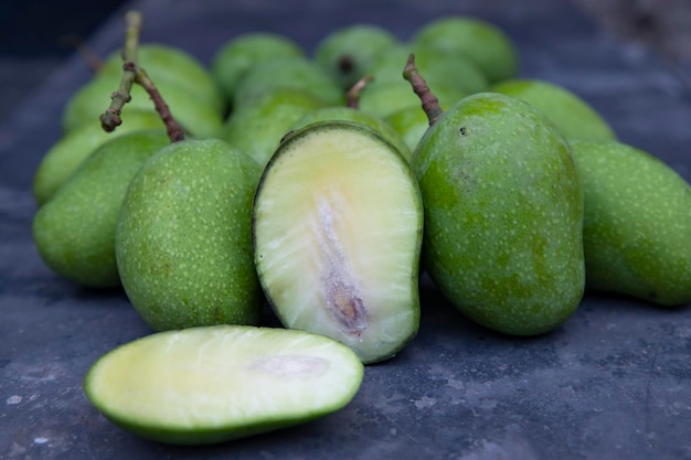 Gros plan sur la mangue crue fraîche avec des tranches de mangue sur le sol en béton Ingrédient de cornichon