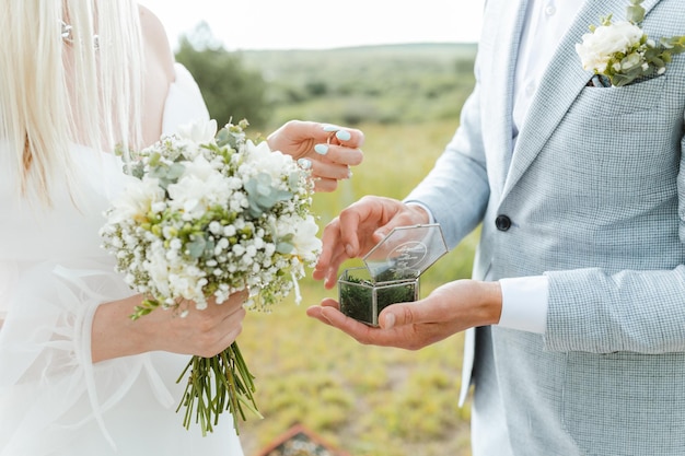 Gros plan de la mariée donnant sa main au marié pour mettre sa bague pendant la cérémonie de mariage