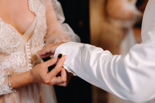 Gros plan de la mariée en sous-vêtements boudoir boutonnant des boutons de manchette sur sa manche