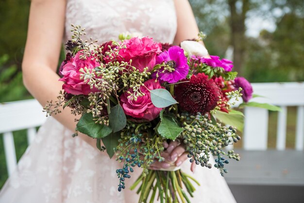 Gros plan d'une mariée tenant un bouquet de roses