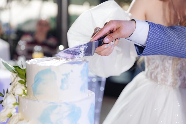 Photo gros plan des mariés coupant le gâteau de mariage ensemble