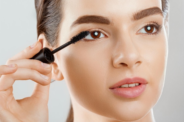 Gros plan de mascara d'une belle jeune femme un visage avec une peau douce fraîche de maquillage de beauté