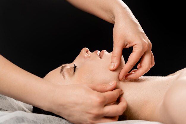 Gros plan sur le massage du visage Le masseur fait des soins de beauté du visage pour un modèle féminin attrayant