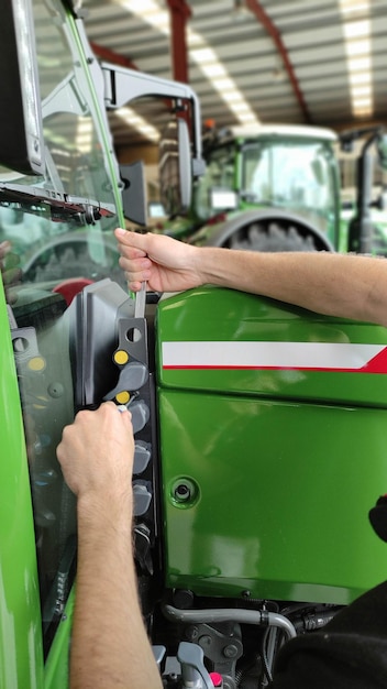 Gros plan sur un mécanicien agricole travaillant sur un tracteur agricole vert dans l'atelier de mécanique