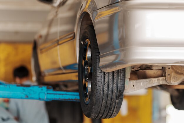 Gros plan Le mécanicien automobile remplace le pneu sur la roue dans l'atelier de réparation automobile.