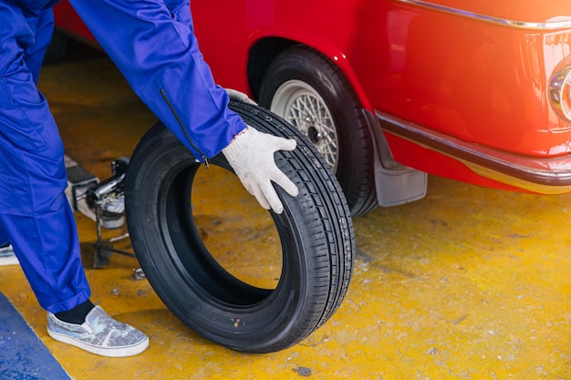 gros plan mécanicien de garage travailleur remplace les pneus de voiture change remplace les roues en caoutchouc dans le concept de centre de service automobile