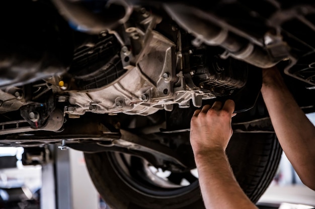 Gros plan d'un mécanicien mains repaires voiture levée