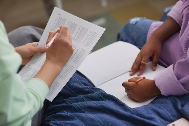 Gros plan d'une mère aidant sa fille à faire ses devoirs à l'intérieur