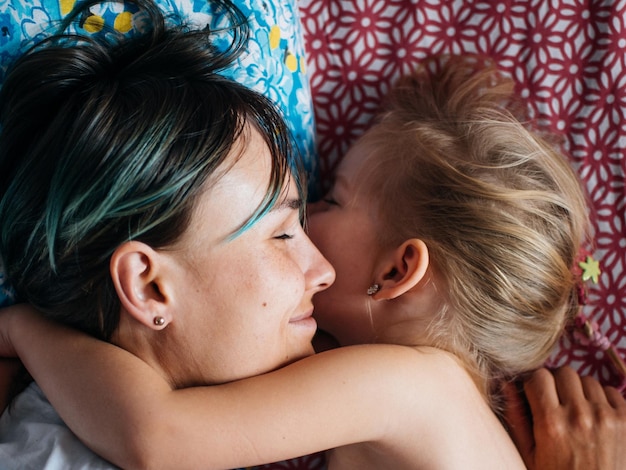 Photo un gros plan d'une mère souriante qui dort avec sa fille sur le lit.