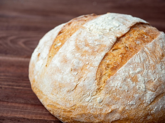 Gros plan d'une miche ronde de pain de blé allongé sur un fond en bois brun Concept de boulangerie de cuisson Vue latérale