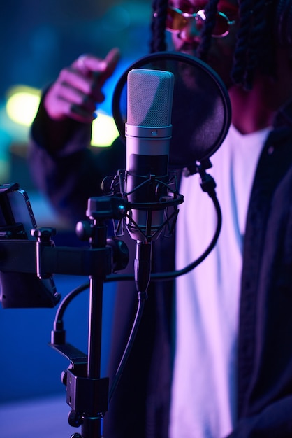 Gros plan sur un microphone dans le studio d'enregistrement avec un chanteur chantant en arrière-plan