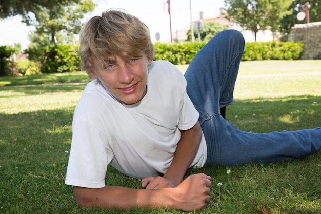 Gros plan d'un mignon jeune garçon adolescent souriant allongé sur l'herbe à la maison