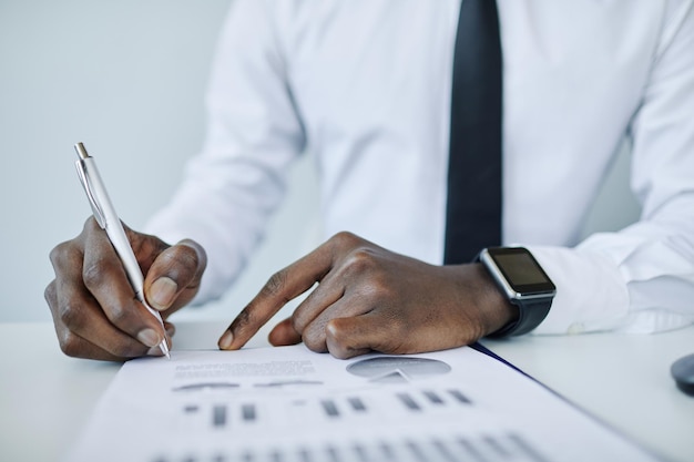 Gros plan minimal de jeune homme d'affaires afro-américain écrivant dans un cahier à l'espace de copie du lieu de travail