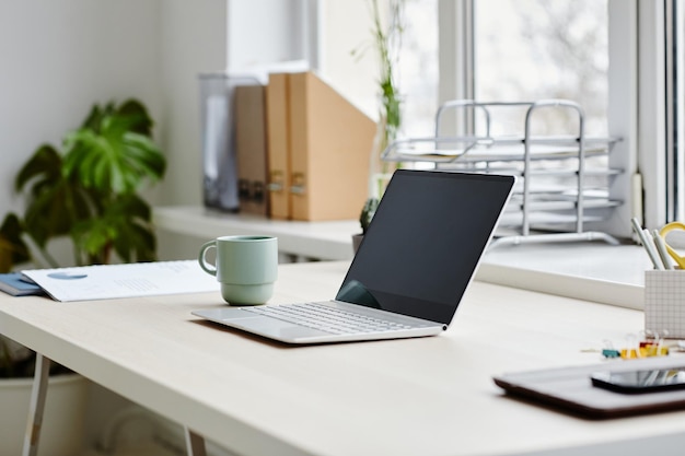 Gros plan minimal d'un ordinateur portable ouvert sur le bureau dans un espace de copie intérieur confortable pour le bureau à domicile