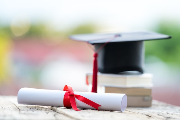 Photo gros plan sur une mise au point sélective d'un chapeau de graduation ou d'un mortier et d'un certificat de diplôme mis sur la table