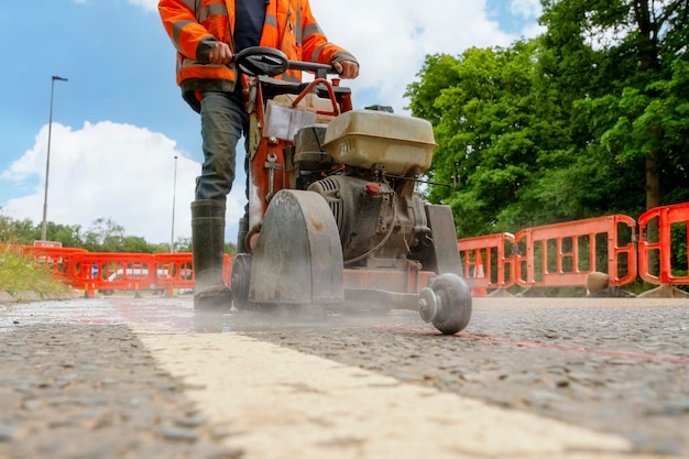 Gros plan et mise au point sélective de la scie routière à essence avec lame coupant la surface de la route en asphalte