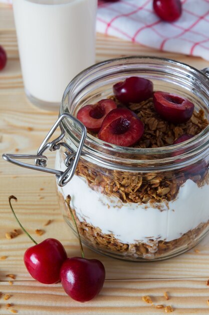 Gros plan de muesli et de yaourt avec des cerises et un verre de lait