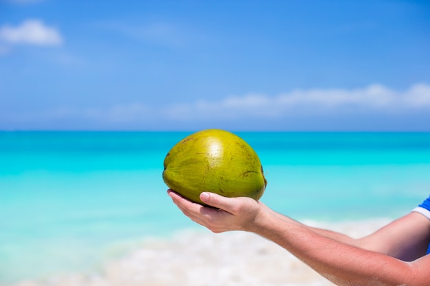 Gros plan de noix de coco dans les mains contre la mer turquoise