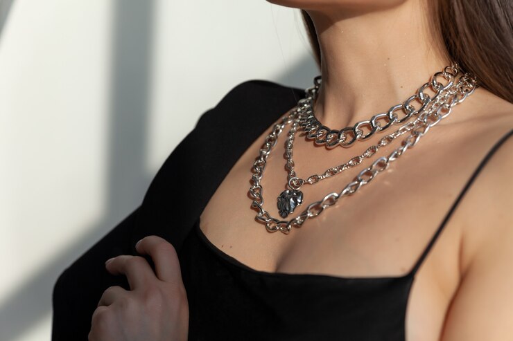 Photo gros plan de nombreuses chaînes en argent modernes avec pendentif en forme de coeur sur le modèle brune aux cheveux longs, collier en métal, lumière du soleil