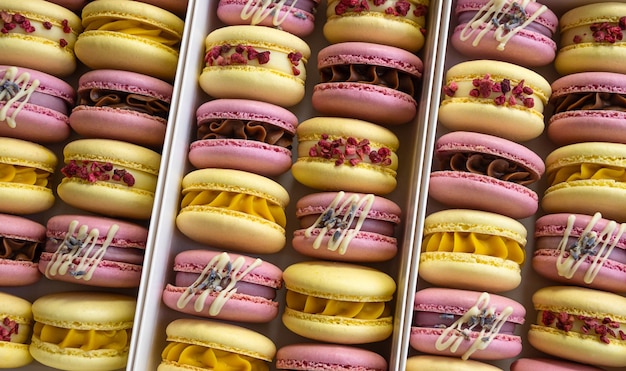 Gros plan sur de nombreux desserts de macarons roses et jaunes avec des goûts différents