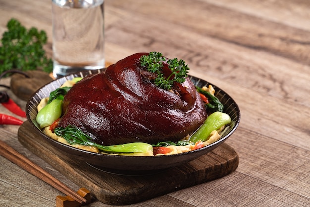 Gros plan de la nourriture taïwanaise de jarret de porc braisé dans une assiette sur fond de table rustique.