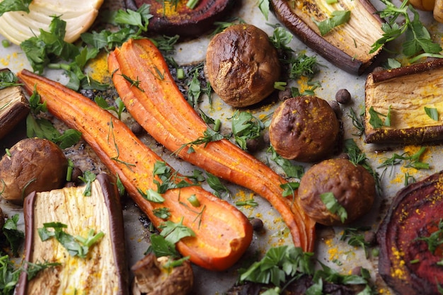 Gros plan sur la nourriture végétarienne Tranches cuites au four d'aubergines betteraves carottes oignons pommes de terre champignons entiers épices et herbes sur papier parchemin