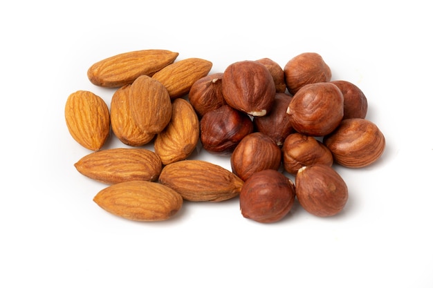 Gros plan de noyaux de noisettes et d'amandes sur fond blanc.