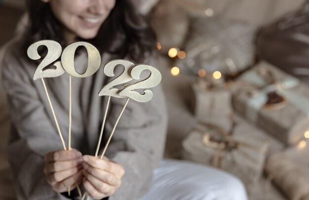 Gros plan des numéros en bois 2022 sur des bâtons dans des mains féminines sur fond flou avec bokeh.