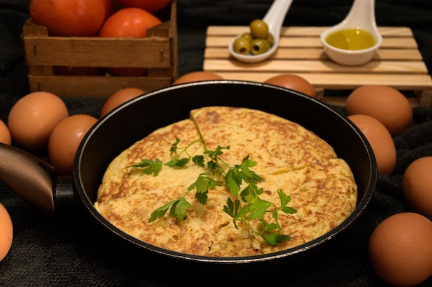 Gros plan d'une omelette dans un torréfacteur noir, des tomates, des œufs frais et du jaune d'œuf