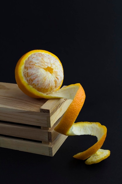 Gros plan sur l'orange pelée sur la boîte en bois le fond noir Espace de copie Emplacement vertical