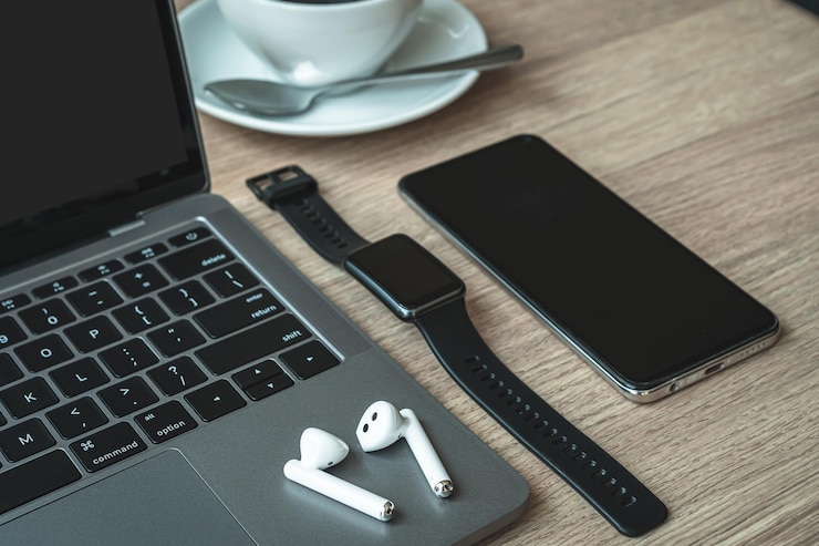 Photo gros plan sur un ordinateur portable à clavier, des écouteurs sans fil avec smartwatch, un café chaud dans une tasse et un écran vide de smartphone sur un bureau de fond en bois dans un café comme l'arrière-plan