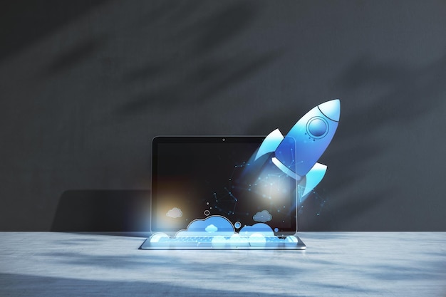 Gros plan sur un ordinateur portable sur le lieu de travail avec une fusée bleue volante brillante sur fond de mur en béton Démarrage et lancement du concept 3D Rendering